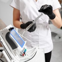 Dentist wearing white uniform and black gloves, working with all-in-one device concept for mechanical root canal treatment. Concept of modern dental endodontic equipment